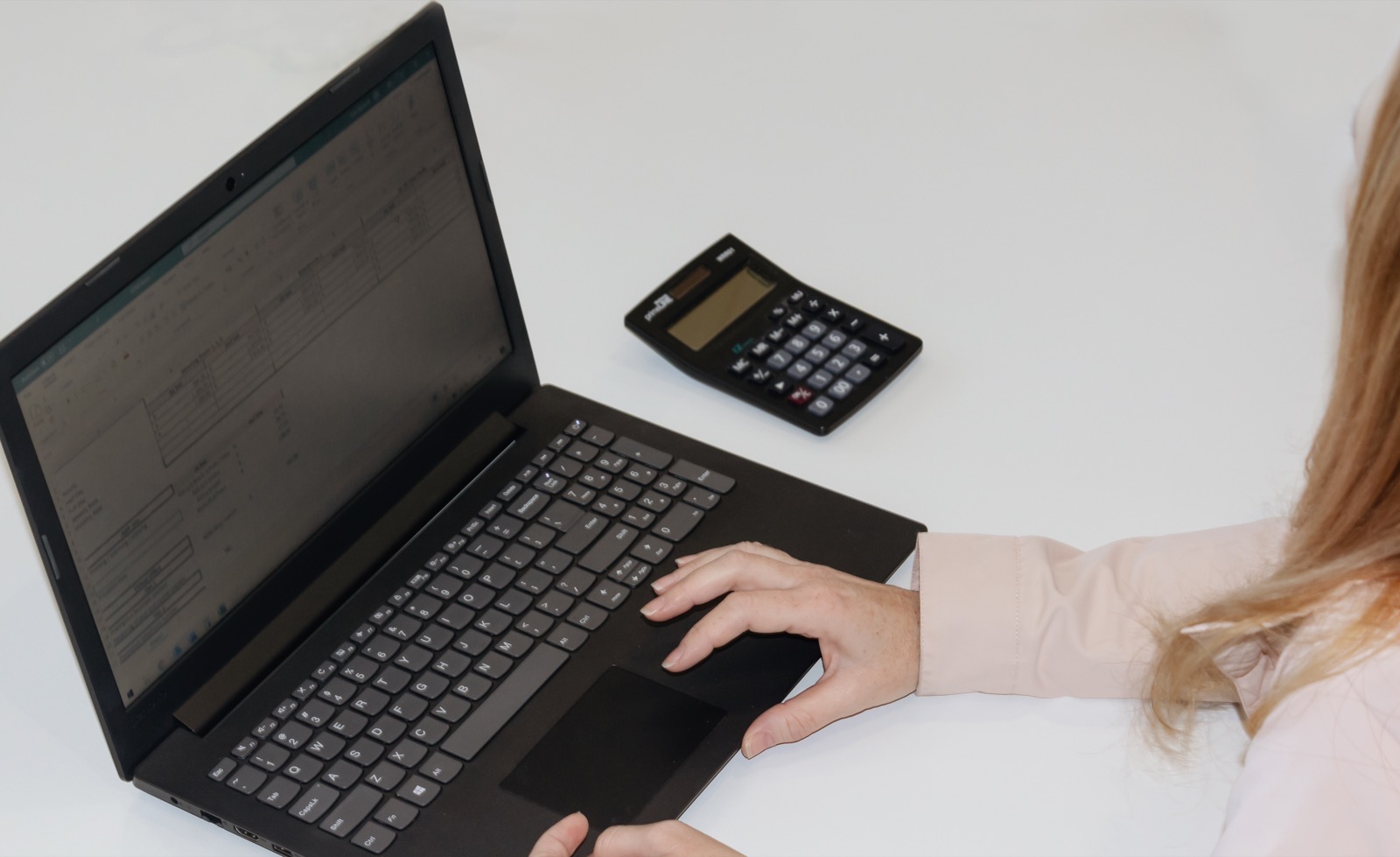 Professional working on laptop with calculator at XEN4